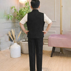 Person wearing a black vest and pants in a room with plants and a pink stool.