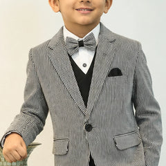 Young boy in a formal gray suit with a white shirt and bow tie on a plain background