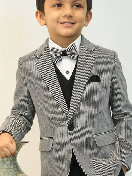 Young boy in a formal gray suit with a white shirt and bow tie on a plain background