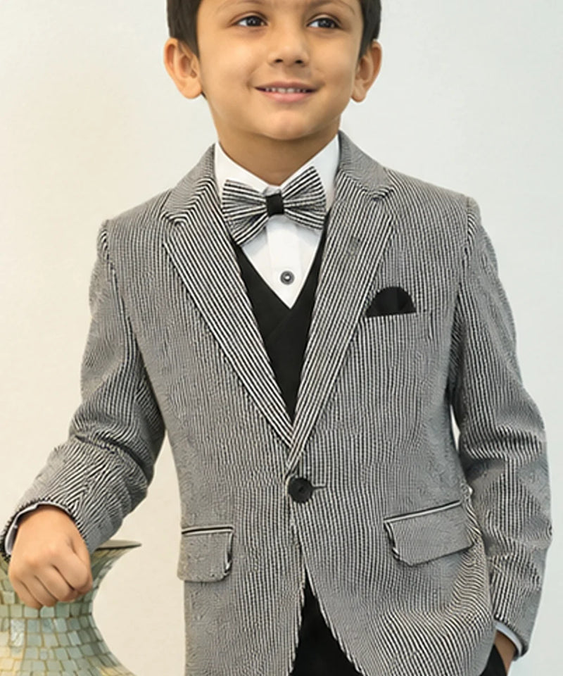 Young boy in a formal gray suit with a white shirt and bow tie on a plain background