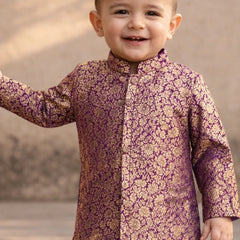 Child wearing a purple and gold traditional outfit with a blurred background