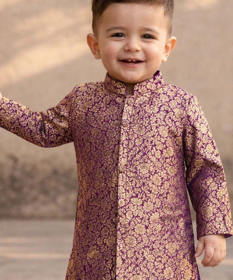 Child wearing a purple and gold traditional outfit with a blurred background