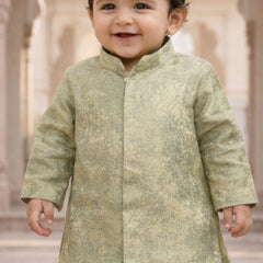 Child wearing a light green traditional outfit with a blurred architectural background