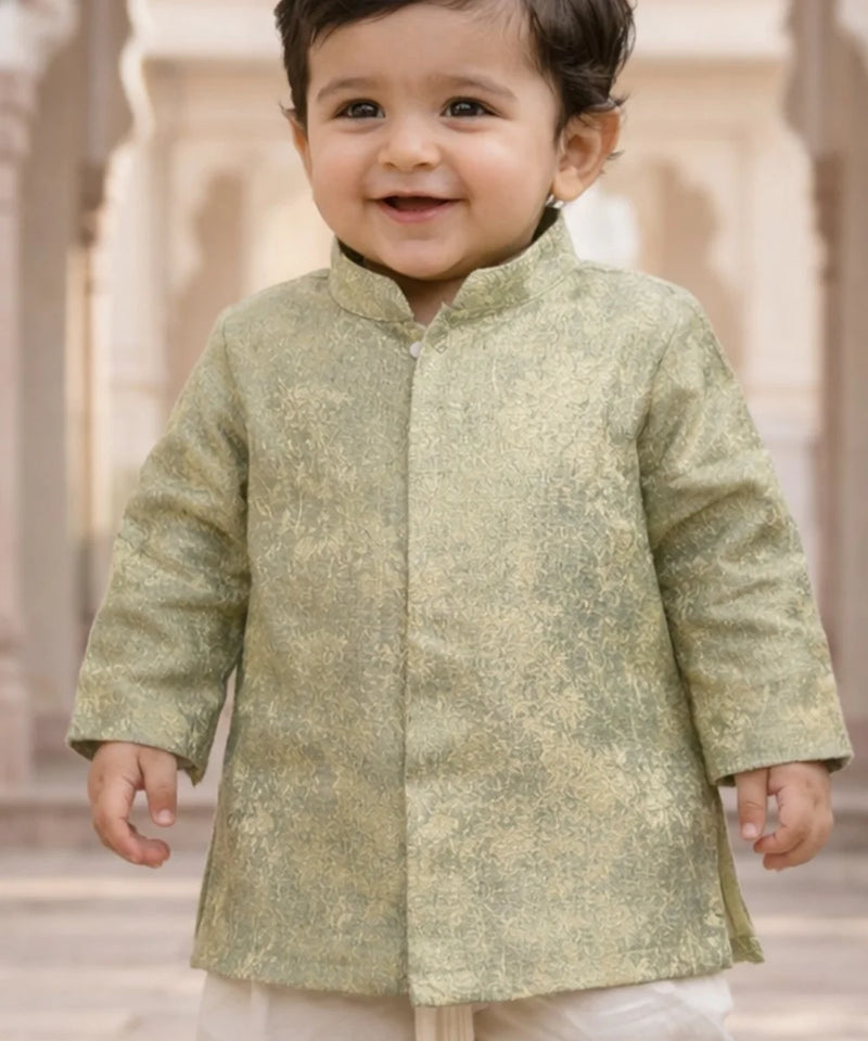 Child wearing a light green traditional outfit with a blurred architectural background