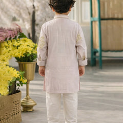 Child wearing a traditional outfit standing in a decorative setting with flowers and a green door.