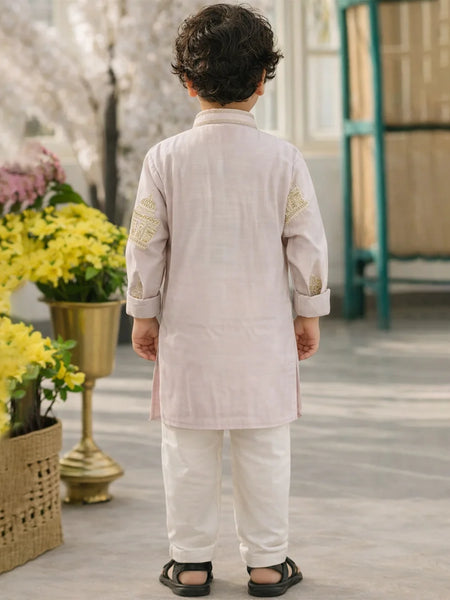 Child wearing a traditional outfit standing in a decorative setting with flowers and a green door.