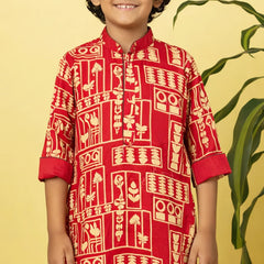 Child wearing a red traditional kurta with white patterns on a yellow background