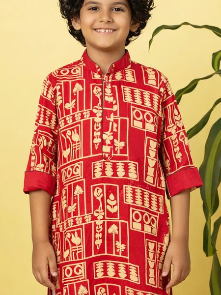 Child wearing a red traditional kurta with white patterns on a yellow background