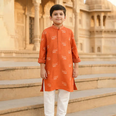 Child wearing an orange kurta with white patterns standing on steps in front of a historic building.