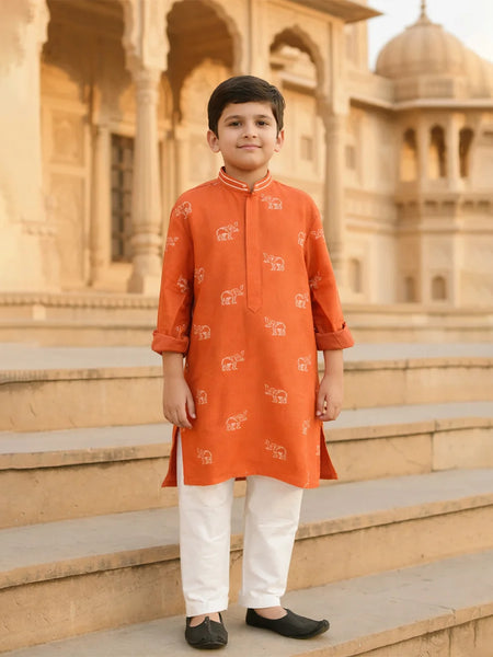 Child wearing an orange kurta with white patterns standing on steps in front of a historic building.