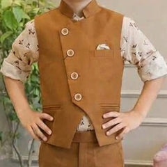 A child wearing a brown Nehru jacket-style vest with four decorative buttons, a chest pocket with a pocket square, and matching brown trousers over a light patterned short-sleeve shirt, standing indoors with hands on hips.
