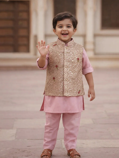 Child wearing a traditional outfit with a gold vest and pink pants, standing outdoors.
