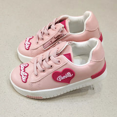 Pink sneakers with a heart-shaped Barbie logo on a light background