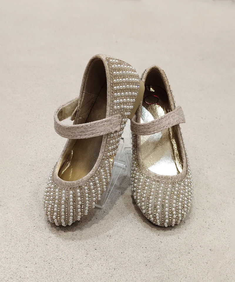 Pair of embellished shoes on a beige background