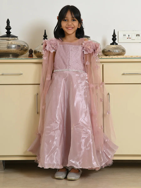 Young girl in a pink dress standing in front of a beige cabinet.
