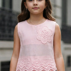 Young girl wearing a pink dress with floral design and lace details.
