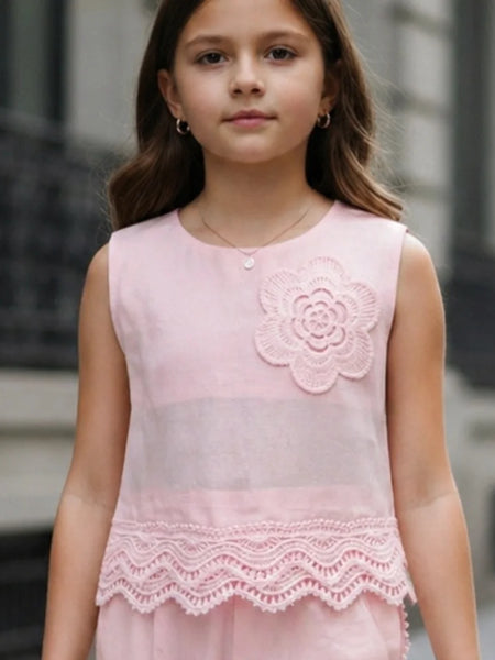 Young girl wearing a pink dress with floral design and lace details.