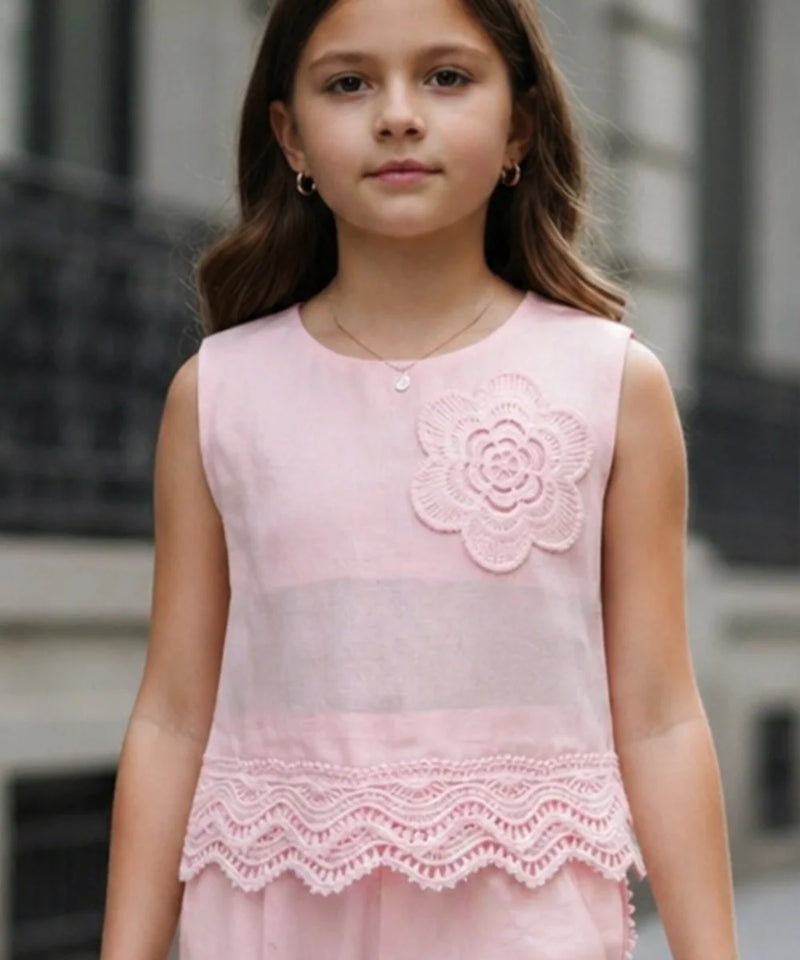 Young girl wearing a pink dress with floral design and lace details.