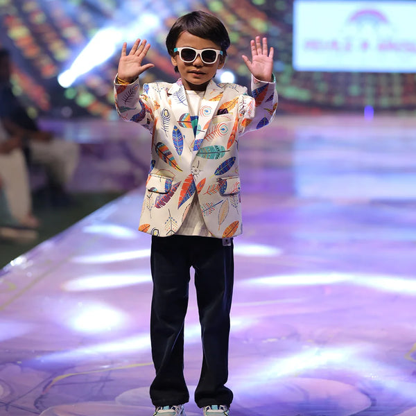 Child model on a fashion show runway wearing a colourful printed blazer.