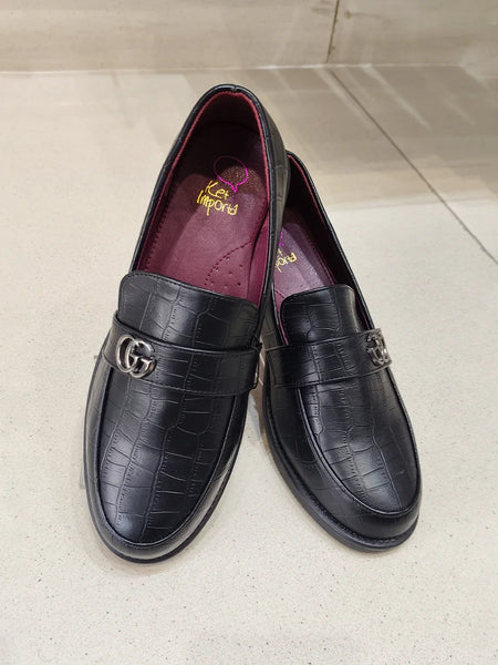 Pair of black leather loafers with a crocodile texture on a light gray surface.