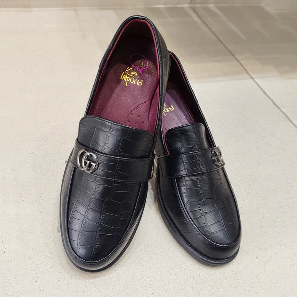 Pair of black leather loafers with a crocodile texture on a light gray surface.