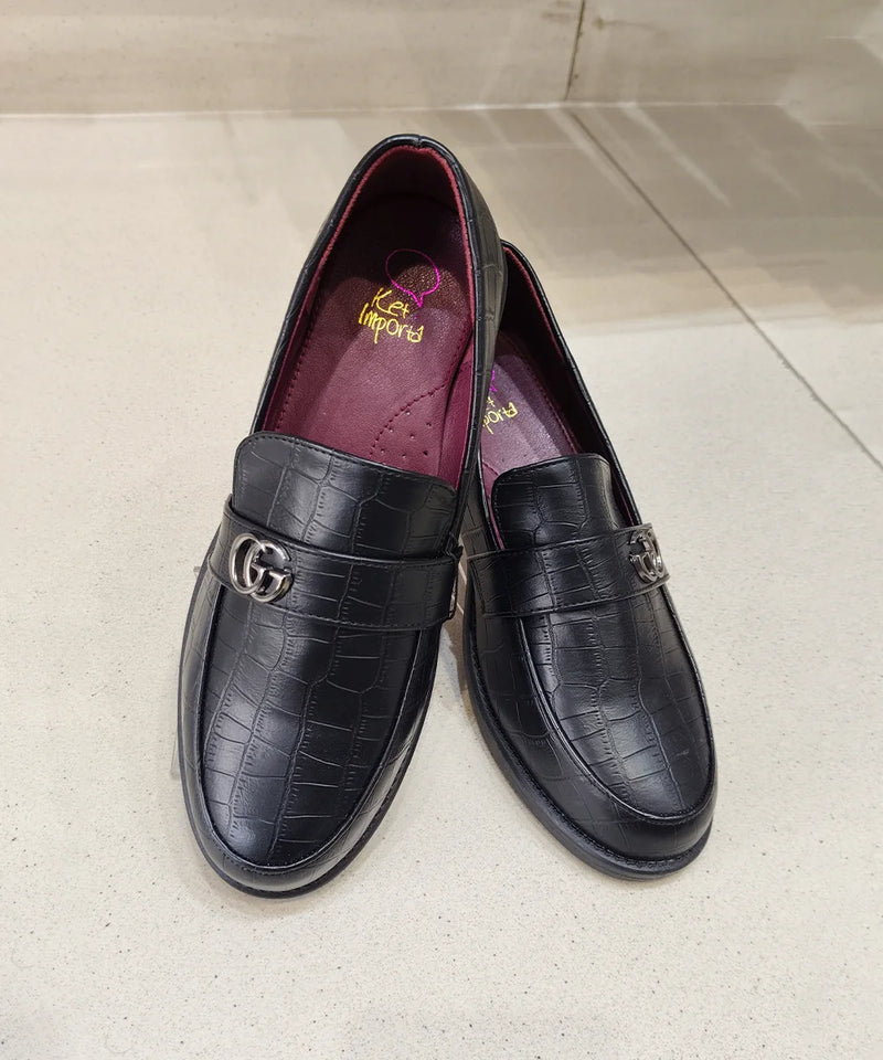 Pair of black leather loafers with a crocodile texture on a light gray surface.