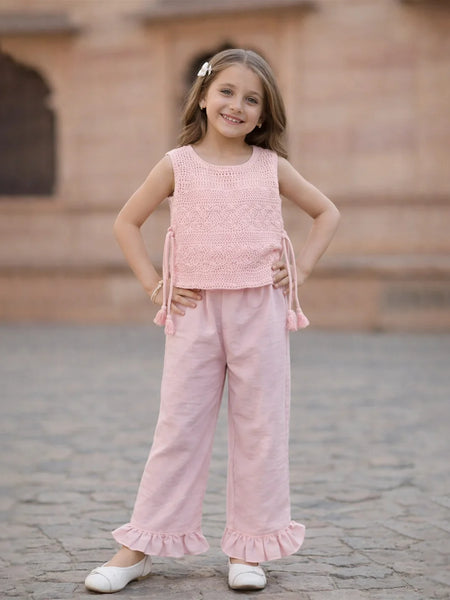 Young girl in a pink outfit standing on a stone pavement.