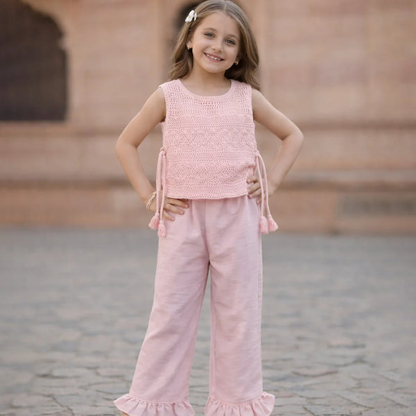 Young girl in a pink outfit standing on a stone pavement.
