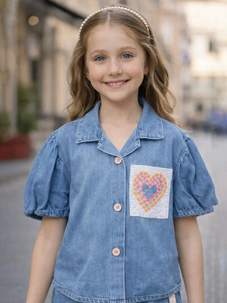 Young girl wearing a blue denim shirt with a heart design on a blurred street background