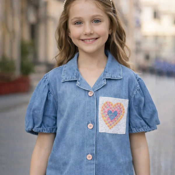 Young girl wearing a blue denim shirt with a heart design on a blurred street background