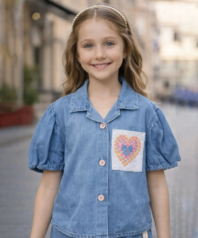 Young girl wearing a blue denim shirt with a heart design on a blurred street background