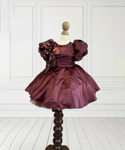 This wine coloured beautiful kids frock with a back zip closure has sequin and pleated detailing on its yoke that adds grace to the look. It features cute bow detailing on the waist curated from sequin fabric. Moreover, it comes with a fabric belt to be tied at the back.