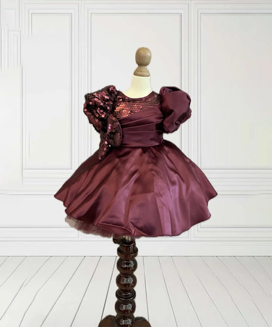 This maroon coloured beautiful kids frock with a back zip closure has sequin and pleated detailing on its yoke that adds grace to the look. It features cute bow detailing on the waist curated from sequin fabric. Moreover, it comes with a fabric belt to be tied at the back.