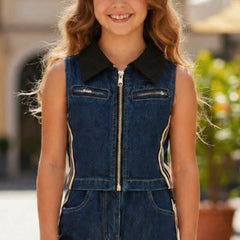 Young girl wearing a denim jumpsuit with a black collar in an outdoor setting.