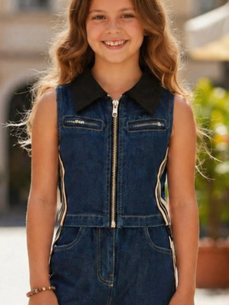 Young girl wearing a denim jumpsuit with a black collar in an outdoor setting.