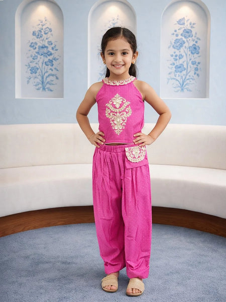 Young girl in a pink traditional outfit standing in a decorated room.