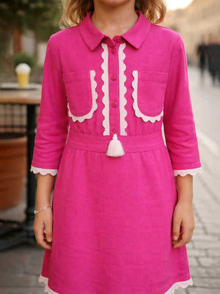 Pink dress with white accents worn by a person, blurred background