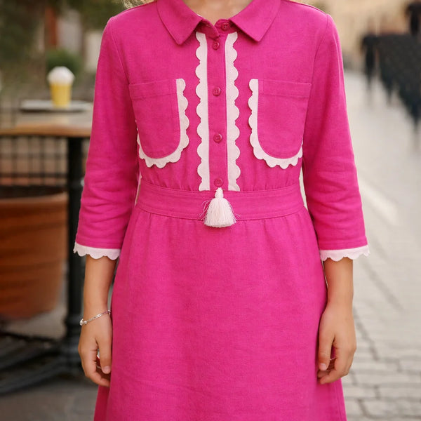 Pink dress with white accents worn by a person, blurred background