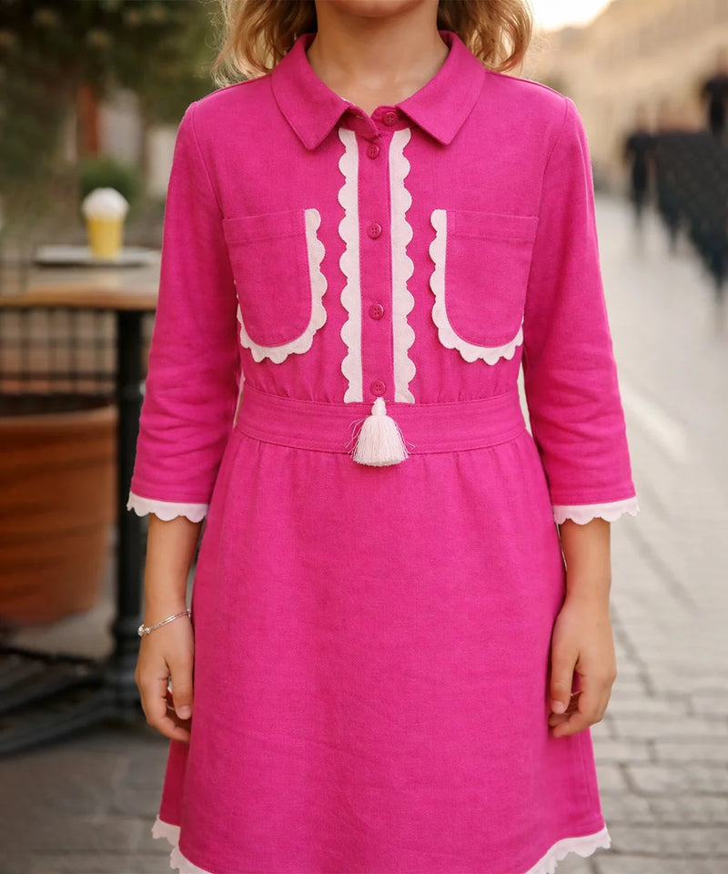 Pink dress with white accents worn by a person, blurred background