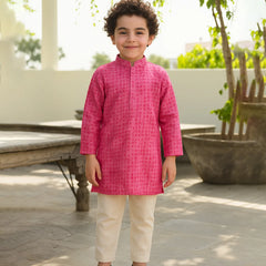 Child wearing a bright pink kurta with white pants outdoors.