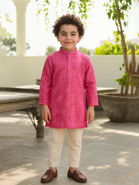 Child wearing a bright pink kurta with white pants outdoors.
