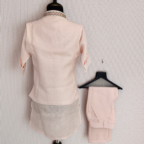 Mannequin wearing a light pink suit with matching pants on a textured white background