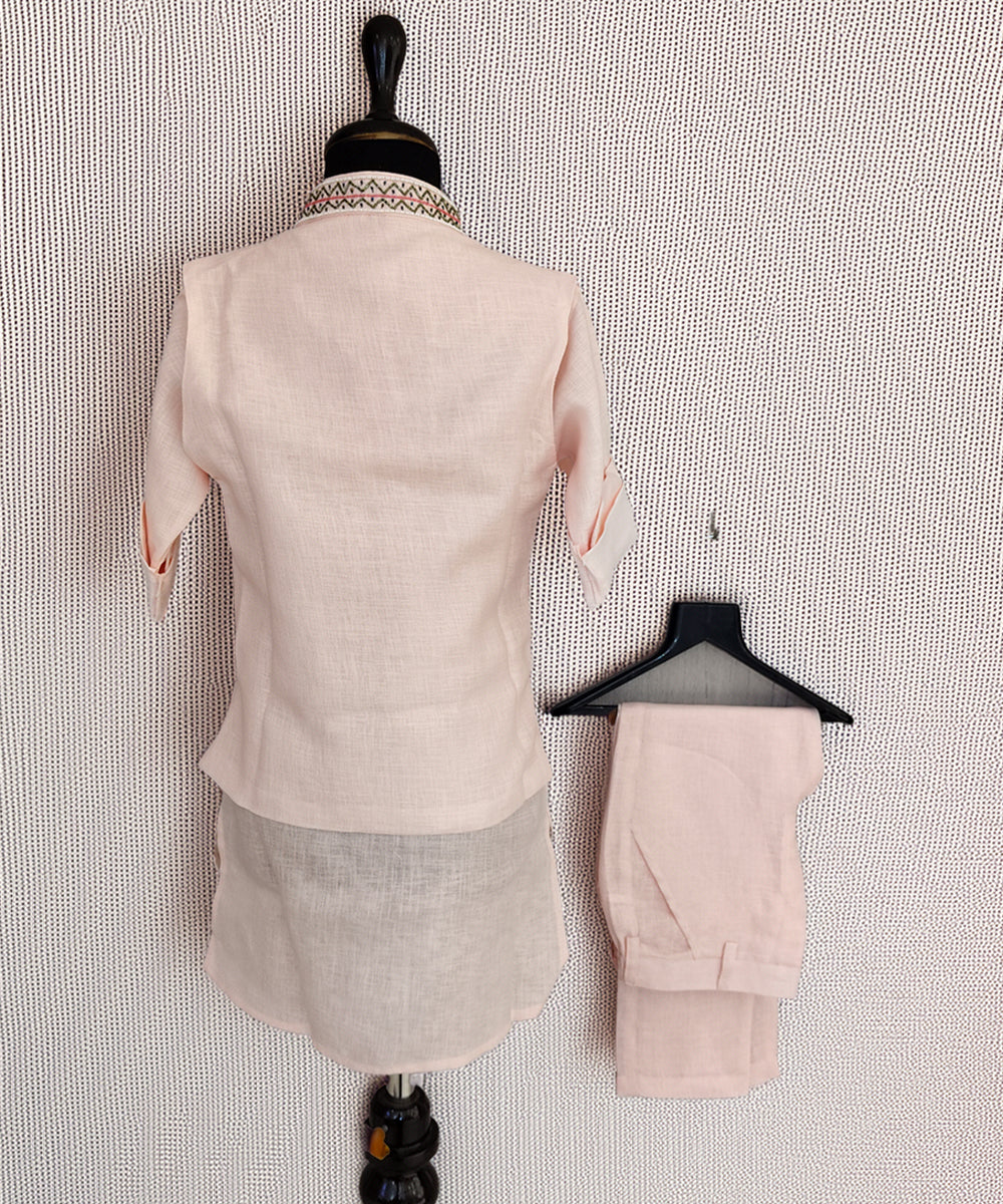 Mannequin wearing a light pink suit with matching pants on a textured white background