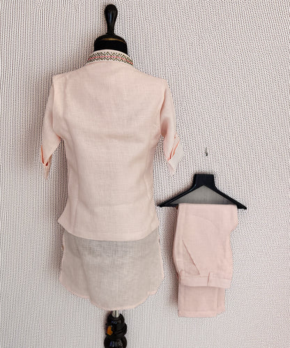 Mannequin wearing a light pink suit with matching pants on a textured white background