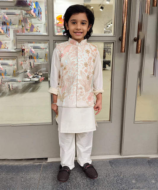 Child wearing a kurta pyjama with a jacket traditional outfit standing in front of a store entrance.