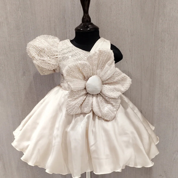 White dress with a large floral bow on a mannequin against a gray background