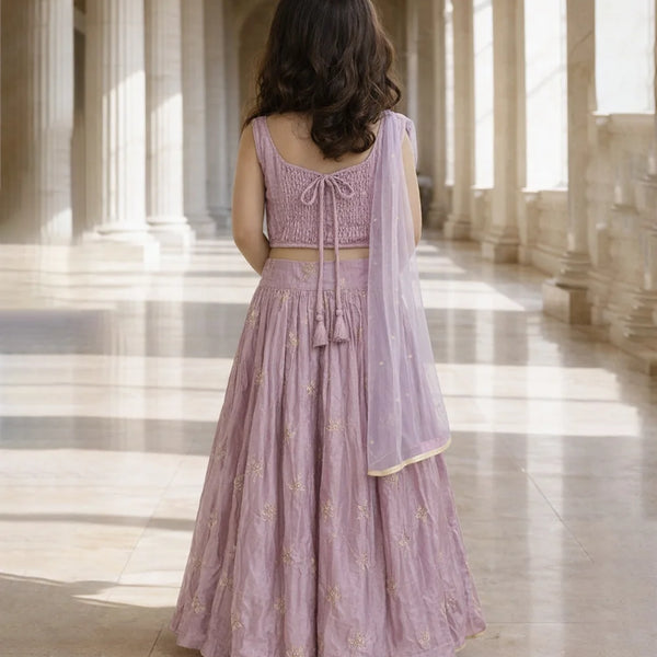 Woman in a lavender traditional outfit standing in a sunlit hallway.