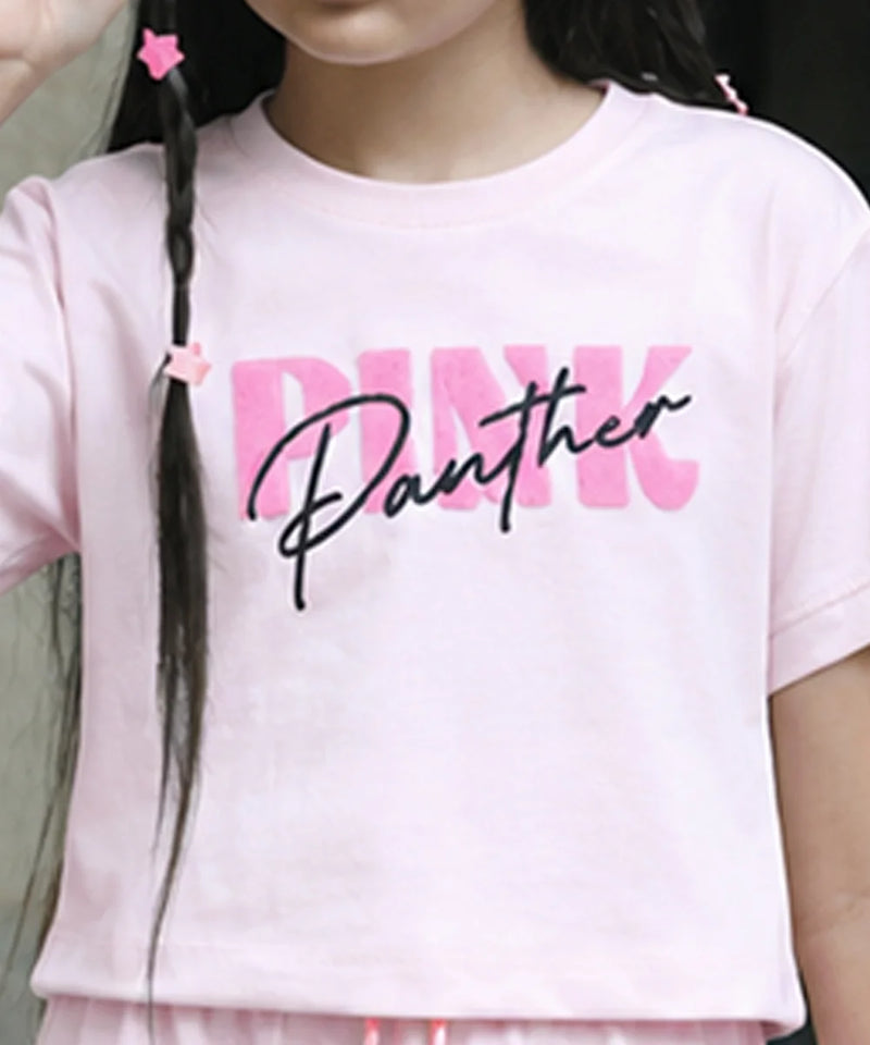 A close-up of a child wearing a light pink short-sleeve T-shirt with a large graphic print reading 'PINK Panther' across the chest. The 'PINK' text is in a bold pink block font, overlaid with 'Panther' in black cursive script.