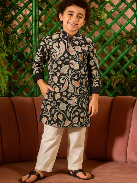 Child wearing a traditional outfit with a floral pattern standing in front of a green lattice wall.