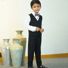 Young boy in a formal outfit standing in front of decorative vases.